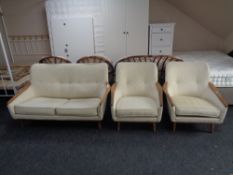 A 20th century teak armed three piece lounge suite upholstered in a cream buttoned brocade fabric