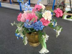 A large antique brass coal bucket containing artificial flowers