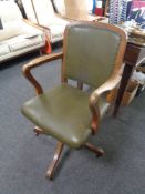 An Edwardian oak swivel desk armchair upholstered in a green button leather