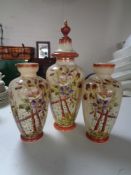 An antique hand painted glass lidded vase depicting flowers together with a further pair of