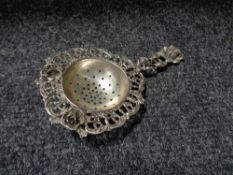 A continental silver strainer decorated with roses