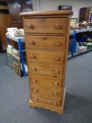 A narrow pine seven drawer chest.