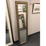 A 5' by 1' hall mirror in decorative gilt frame