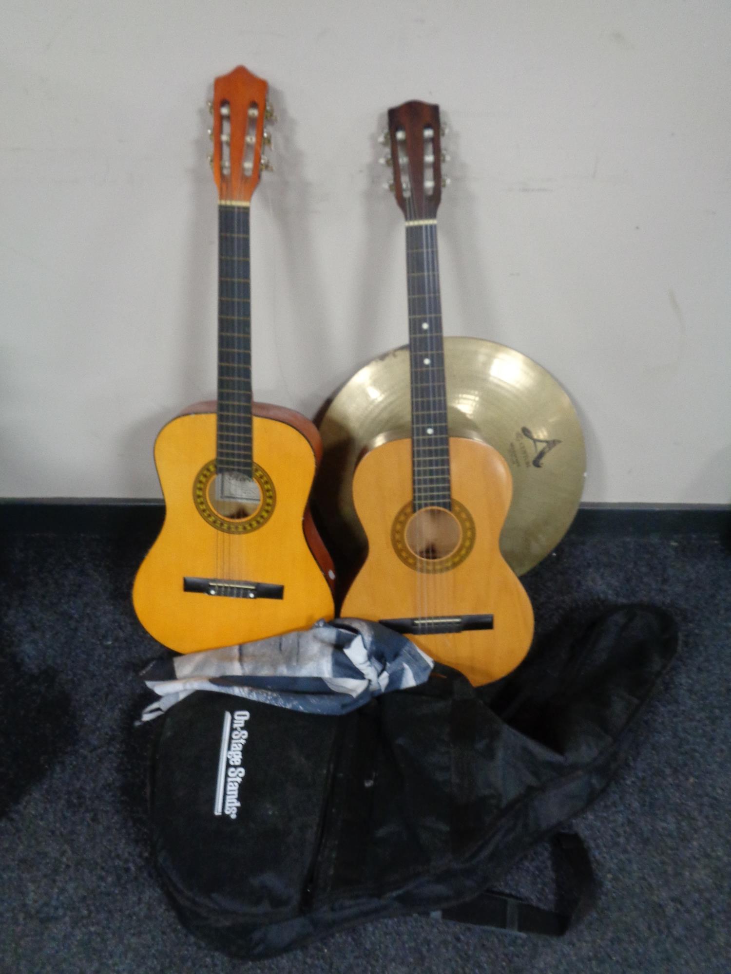 Two acoustic guitars, one in carry bag, together with a cymbal.