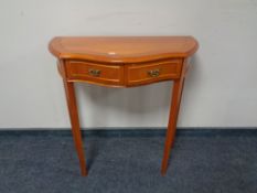 An inlaid yew wood shaped front hall table, fitted two drawers.