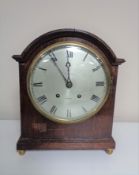 An Edwardian bracket clock with silver dial by Whittaker of Oldham on raised brass feet.