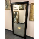 A 5' by 2' mirror in a black and gilt frame