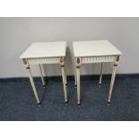 A pair of white and gilt lamp tables on reeded legs.