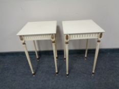 A pair of white and gilt lamp tables on reeded legs.
