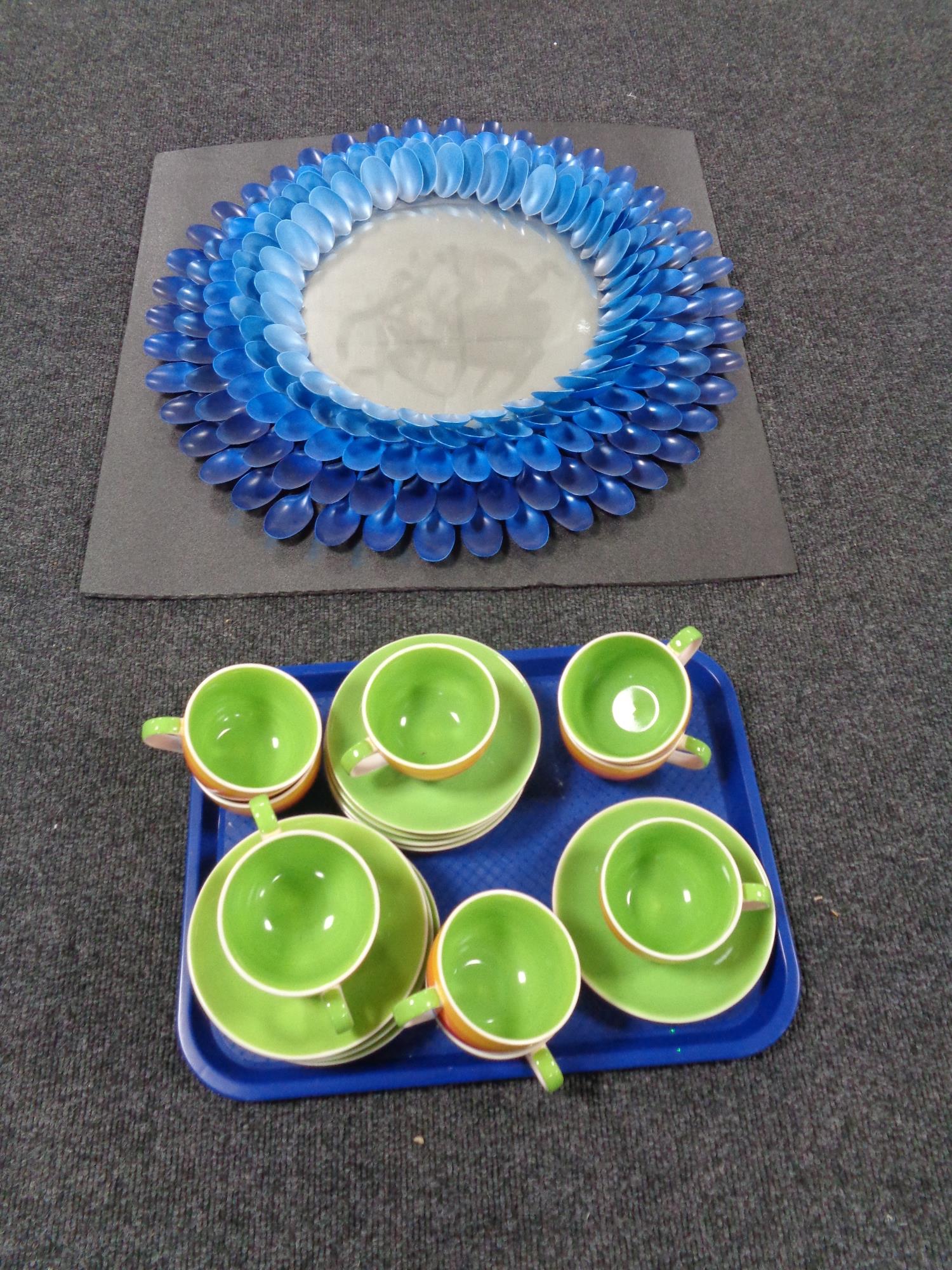 A circular contemporary mirror together with a tray containing Jones teacups and saucers