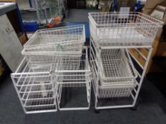Three metal stands together with a quantity of white wire metal baskets.