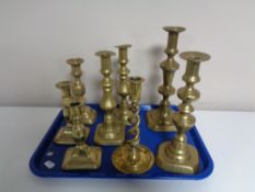 A tray containing a pair of antique brass candlesticks together with six further brass candlesticks.