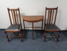 A 20th century teak demi lune table together with a pair of Edwardian oak dining chairs.