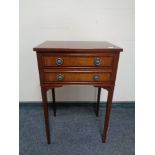 A Regency style inlaid mahogany two drawer chest on raised legs.