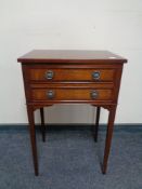 A Regency style inlaid mahogany two drawer chest on raised legs.