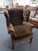 A wingback armchair upholstered in a brown button dralon.