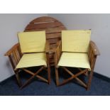 A circular teak folding garden table together with four director style chairs.