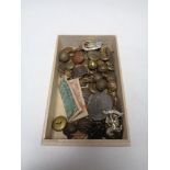 A box containing a collection of military badges and buttons, Edward VII coronation medal etc.
