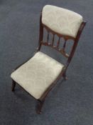 An Edwardian mahogany bedroom chair upholstered in a cream floral fabric.