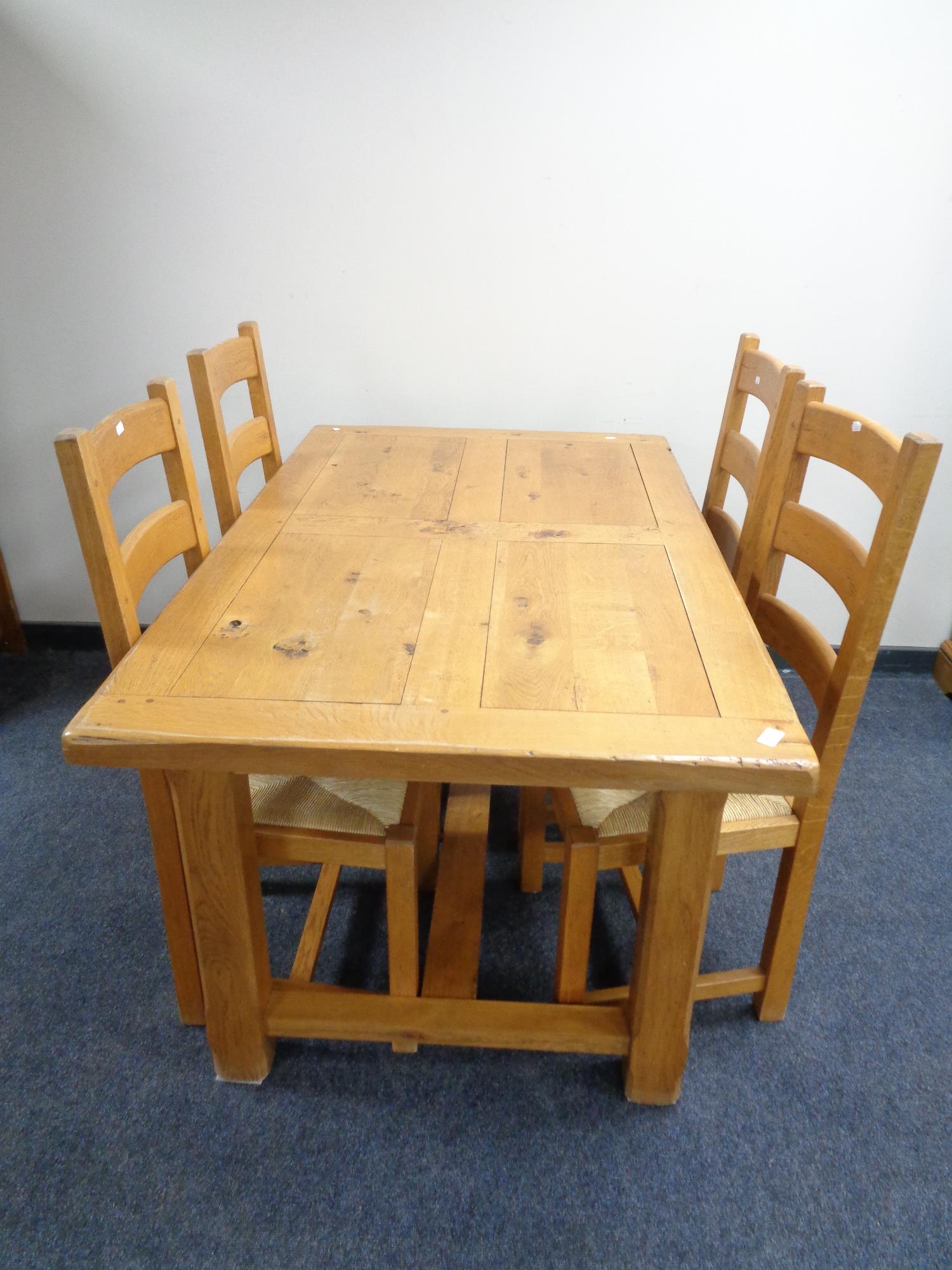 A contemporary oak refectory dining table together with a set of four ladder back rush seated
