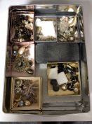 A tin containing a quantity of assorted costume jewellery.