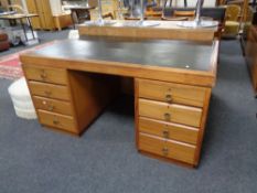 A 20th century teak twin pedestal desk fitted eight drawers with a leather inset panel.