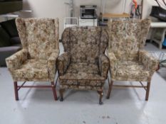 A pair of wingback fireside chairs upholstered in a floral fabric,