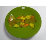 A large Poole Pottery circular plaque, olive green with abstract orange and yellow decoration,