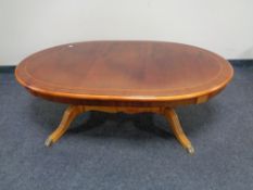 An oval inlaid mahogany coffee table with under stretcher and brass capped feet.