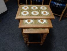 A nest of three blonde oak tile topped tables.