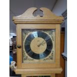 A blonde oak long cased clock by Agria with weights.