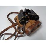 A pair of antique Helinox German binoculars in a fitted leather case.