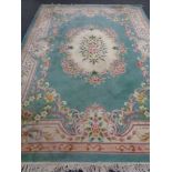 A large Chinese floral embossed fringed carpet on green ground,