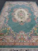 A large Chinese floral embossed fringed carpet on green ground,