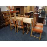 A blonde oak refectory dining table together with a set of seven dining chairs upholstered in an