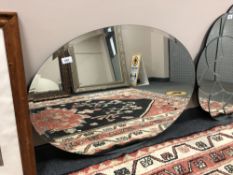 A frameless oval mirror, width 89 cm.