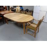 An oval blond oak extending dining table with two leaves and a set of four chairs in green striped