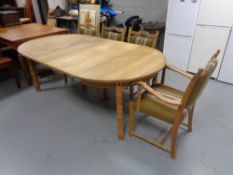 An oval blond oak extending dining table with two leaves and a set of four chairs in green striped