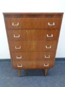 A mid 20th century teak five drawer chest on raised legs.