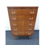 A mid 20th century teak five drawer chest on raised legs.