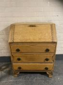A 20th century blond oak writing bureau fitted three drawer beneath