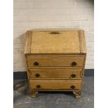 A 20th century blond oak writing bureau fitted three drawer beneath