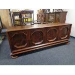 A 20th century continental oak four door low sideboard on bun feet.