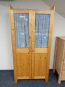 A pine double door storage cupboard.