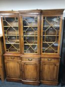 A yew wood triple door break front bookcase with astral glaze doors,