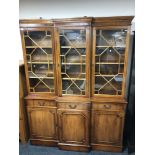 A yew wood triple door break front bookcase with astral glaze doors,