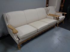 A blond oak framed three seater settee and armchair in cream fabric