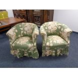 A pair of early 20th century tub chairs upholstered in a green floral fabric on Queen Anne legs.