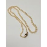 A 21" strap of pearls with 9ct gold pearl and garnet clasp