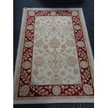 A machine made woolen rug of floral design on cream ground